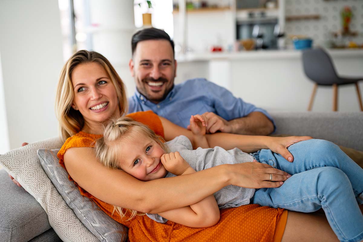parents on couch with their young daughter at home