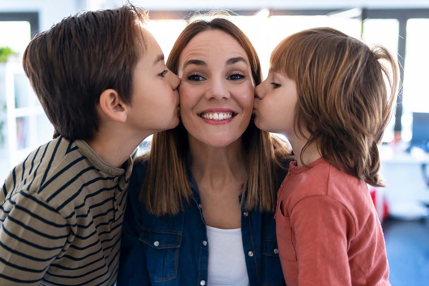 two young boys giving their mother a kiss on the cheek