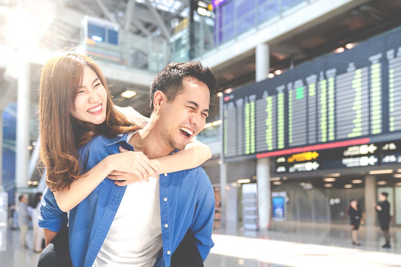 Ask Focal Point Financial Services about Travel Insurance happy young couple excited for their vacation at the airport